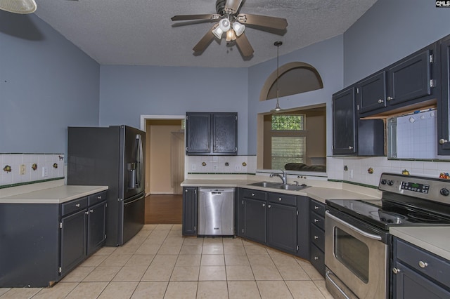 kitchen with stainless steel appliances, a sink, tasteful backsplash, ceiling fan, and a textured ceiling