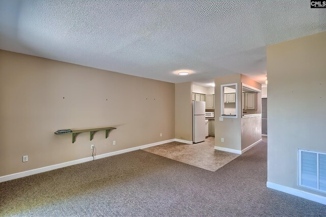 unfurnished living room featuring carpet, a textured ceiling, and baseboards