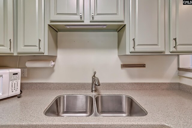 kitchen featuring a sink, white microwave, and light countertops