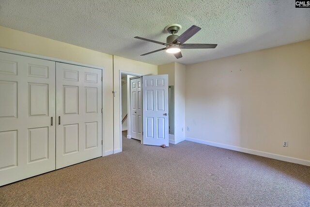 unfurnished bedroom with carpet floors, a textured ceiling, baseboards, a closet, and a ceiling fan