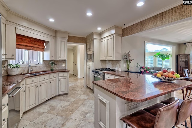 kitchen featuring stainless steel appliances, a sink, a peninsula, a breakfast bar, and crown molding