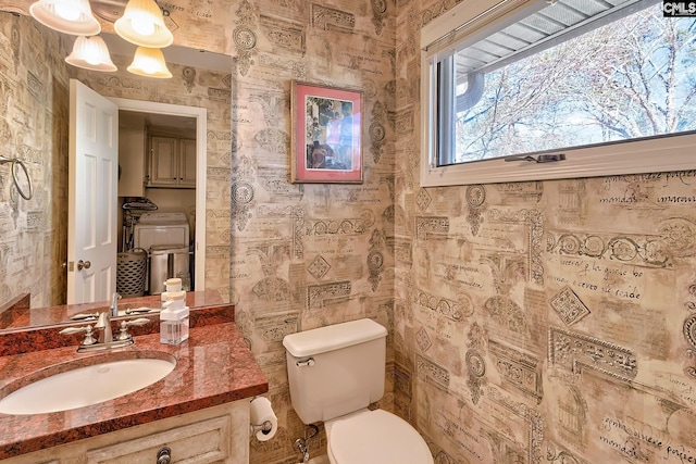 half bath with toilet, separate washer and dryer, and vanity