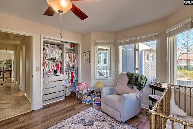 sitting room featuring attic access, ceiling fan, wood finished floors, and baseboards