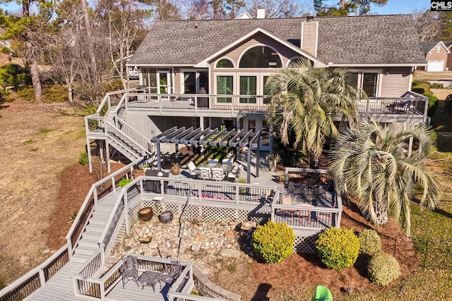 rear view of property featuring stairs, roof with shingles, a chimney, and a deck