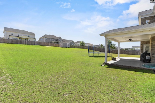 view of yard with a trampoline, ceiling fan, a patio, a shed, and a residential view