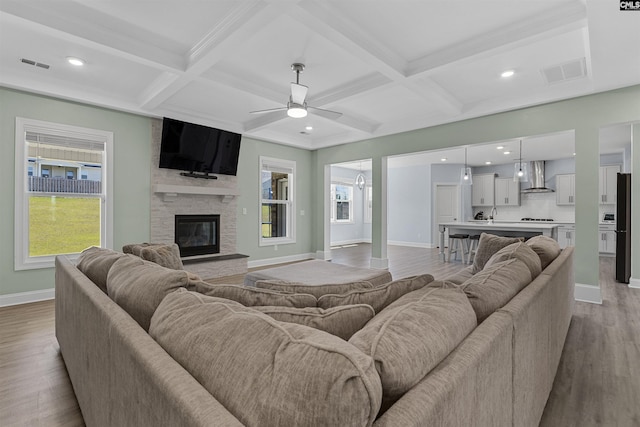 living area featuring baseboards, coffered ceiling, a ceiling fan, plenty of natural light, and wood finished floors