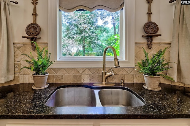 kitchen view of a sink, dark stone countertops, and tasteful backsplash