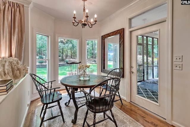dining room featuring light wood finished floors, healthy amount of natural light, a chandelier, crown molding, and baseboards