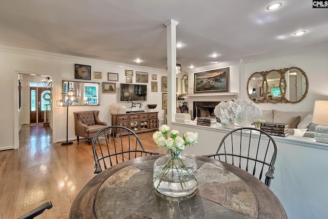 dining space with ornamental molding, wood finished floors, a fireplace, and recessed lighting