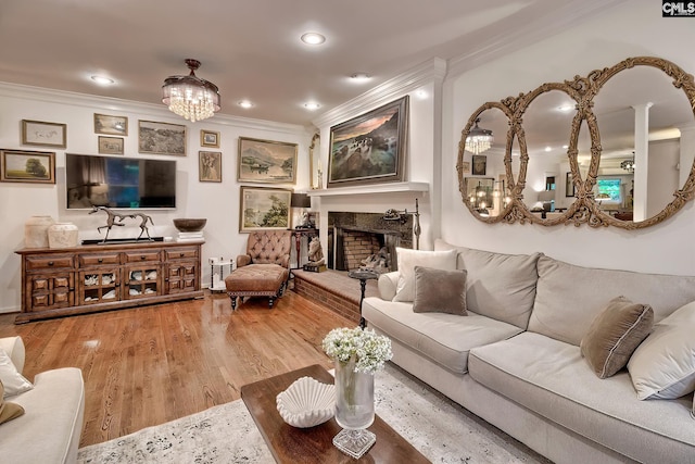 living room with crown molding, wood finished floors, a chandelier, recessed lighting, and a fireplace with raised hearth
