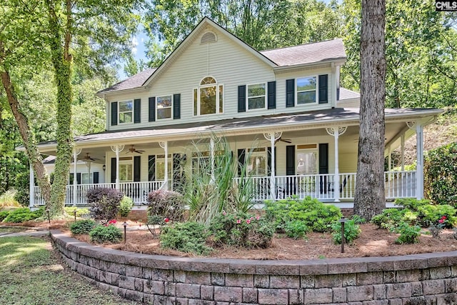 view of front facade with a ceiling fan, covered porch, and roof with shingles