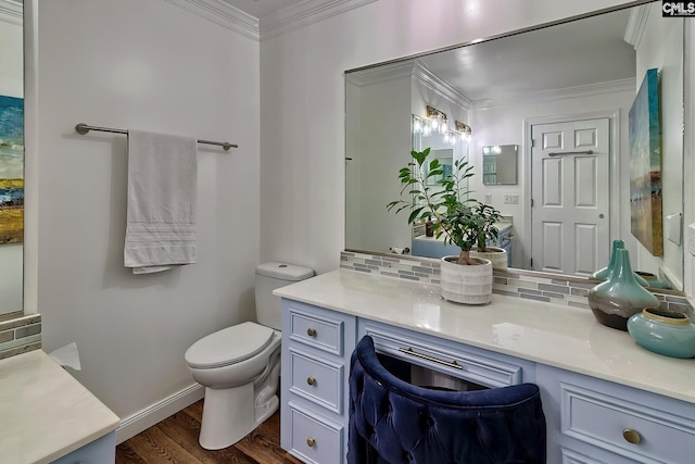 bathroom with ornamental molding, toilet, wood finished floors, backsplash, and vanity