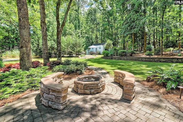 view of patio / terrace featuring a fire pit, an outbuilding, and a wooded view