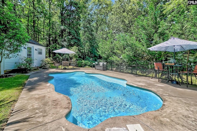 view of swimming pool featuring a patio area, outdoor dining area, fence, and an outdoor structure