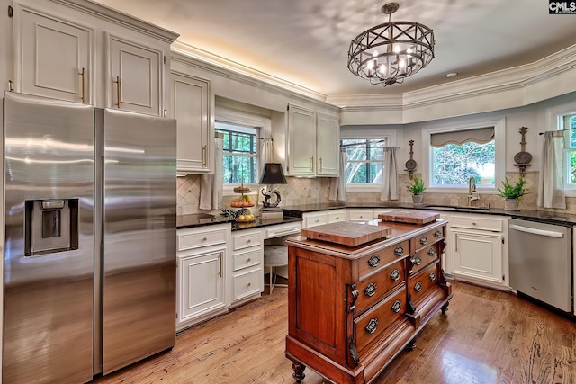 kitchen featuring stainless steel appliances, dark countertops, a sink, a chandelier, and tasteful backsplash