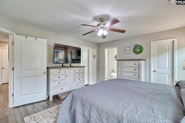 bedroom featuring wood finished floors, ceiling fan, ensuite bathroom, and baseboards