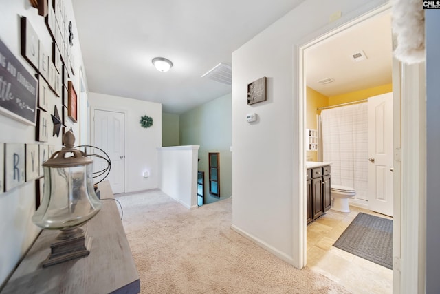 hallway featuring an upstairs landing, light carpet, and baseboards