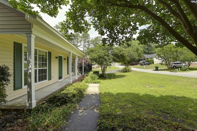 view of green lawn with covered porch