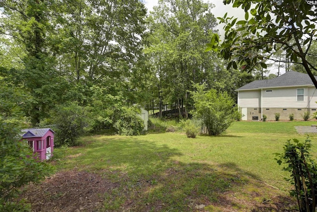 view of grassy yard with a storage shed and an outbuilding