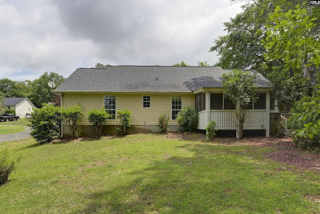 back of house featuring a lawn, a sunroom, and a shingled roof