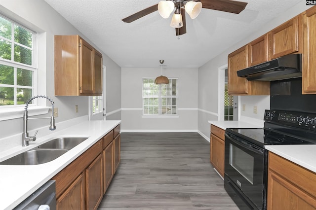 kitchen with electric range, under cabinet range hood, a sink, light countertops, and a textured ceiling