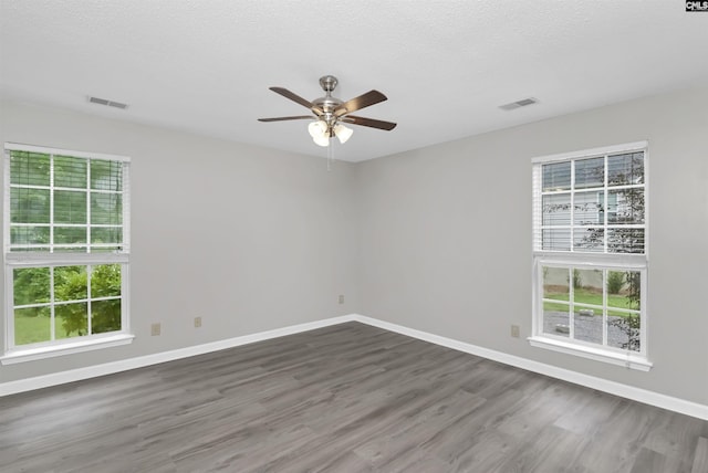 empty room featuring a ceiling fan, baseboards, dark wood-style flooring, and a textured ceiling