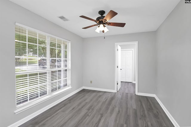 spare room featuring baseboards, wood finished floors, and a ceiling fan