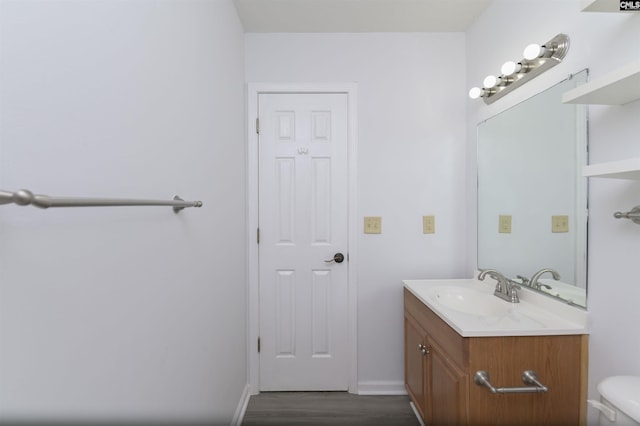 half bath featuring wood finished floors, vanity, toilet, and baseboards