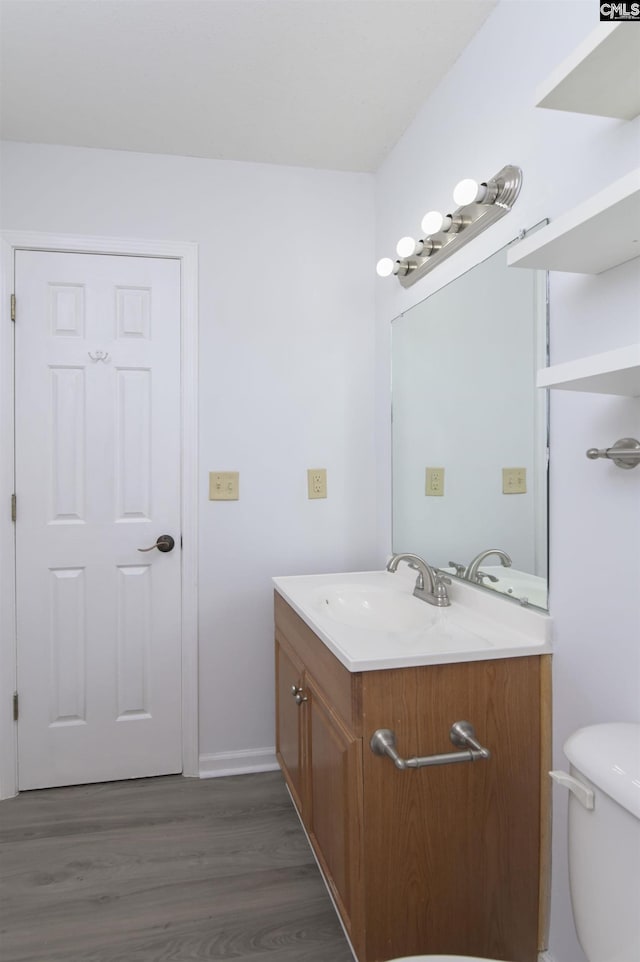 half bathroom featuring vanity, wood finished floors, and toilet