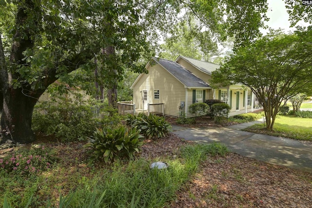 view of side of property with roof with shingles and a deck