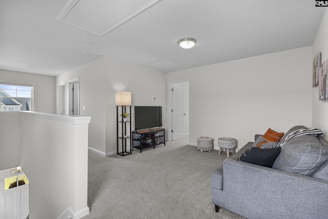 living room with attic access, carpet floors, and baseboards