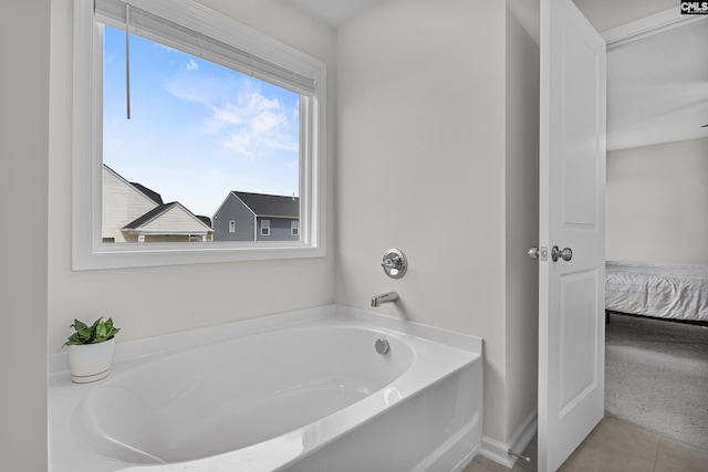 ensuite bathroom featuring a bath and tile patterned flooring