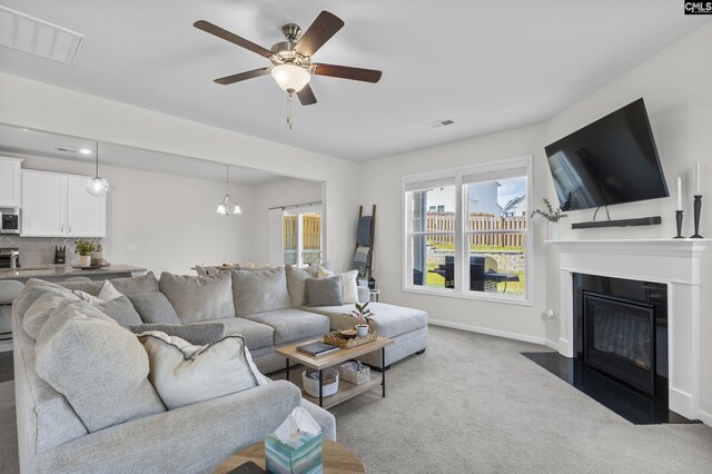 carpeted living area featuring ceiling fan, a fireplace with flush hearth, and baseboards