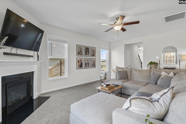 carpeted living area with ceiling fan, a fireplace with flush hearth, and baseboards