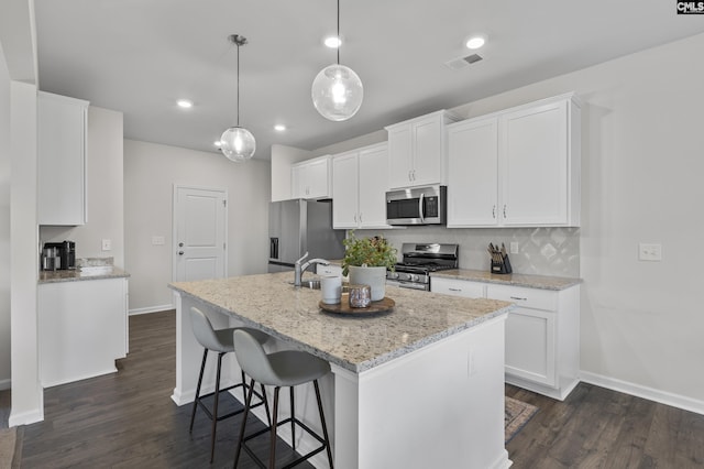 kitchen featuring appliances with stainless steel finishes, baseboards, dark wood-style flooring, a kitchen island with sink, and recessed lighting