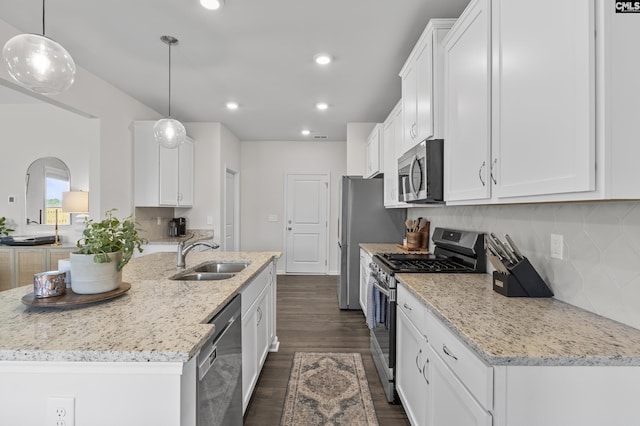 kitchen with appliances with stainless steel finishes, a sink, white cabinets, dark wood-type flooring, and backsplash