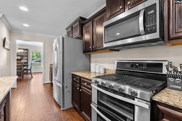 kitchen featuring appliances with stainless steel finishes, ornamental molding, dark brown cabinetry, dark wood-style flooring, and light stone counters