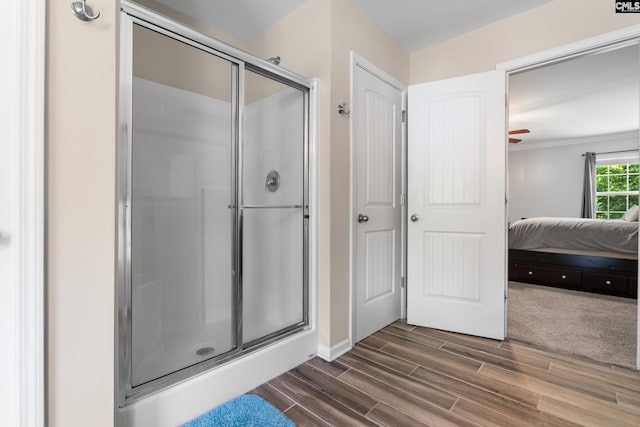 ensuite bathroom featuring wood finished floors, a stall shower, and baseboards