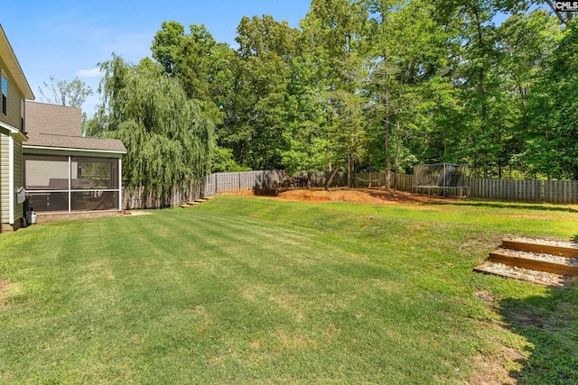 view of yard with a trampoline and a sunroom