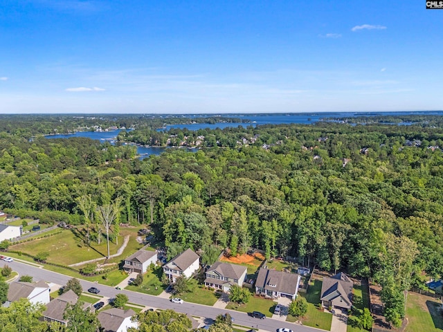 aerial view of property and surrounding area with a heavily wooded area, a nearby body of water, and nearby suburban area