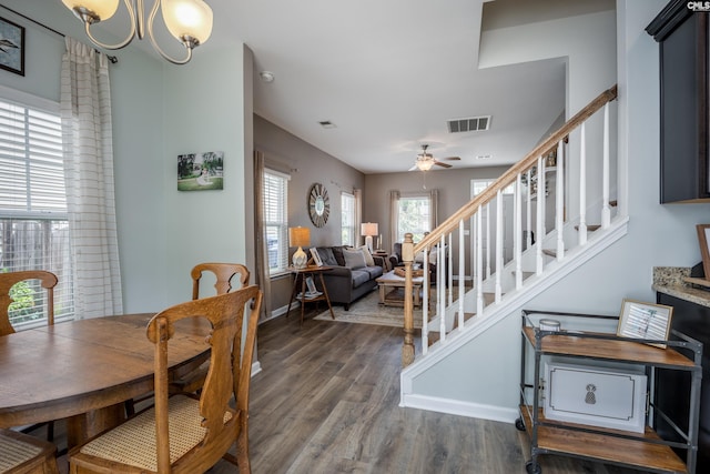 dining space featuring wood finished floors, stairway, a chandelier, and a ceiling fan