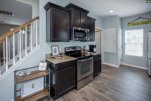 kitchen featuring appliances with stainless steel finishes, dark wood finished floors, baseboards, light stone countertops, and recessed lighting