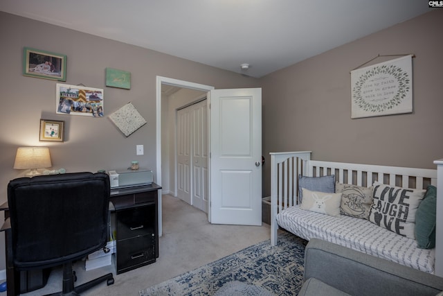 bedroom featuring a desk, light carpet, and a closet