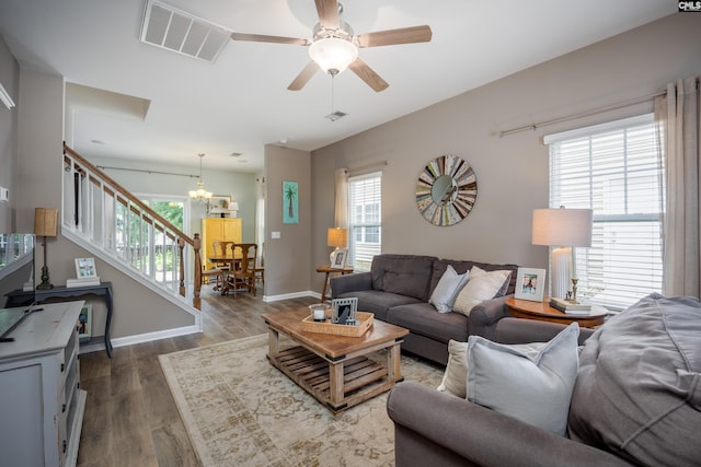 living room featuring stairs, a chandelier, plenty of natural light, and dark wood finished floors