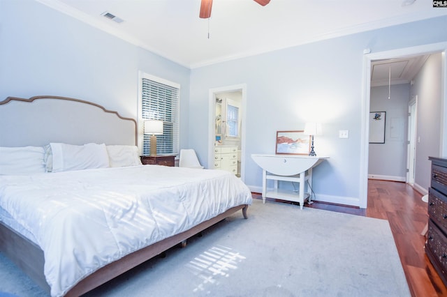 bedroom featuring attic access, crown molding, wood finished floors, baseboards, and a ceiling fan