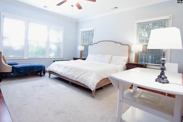 carpeted bedroom with crown molding and a ceiling fan