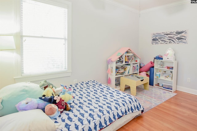 bedroom with wood finished floors, ornamental molding, and baseboards