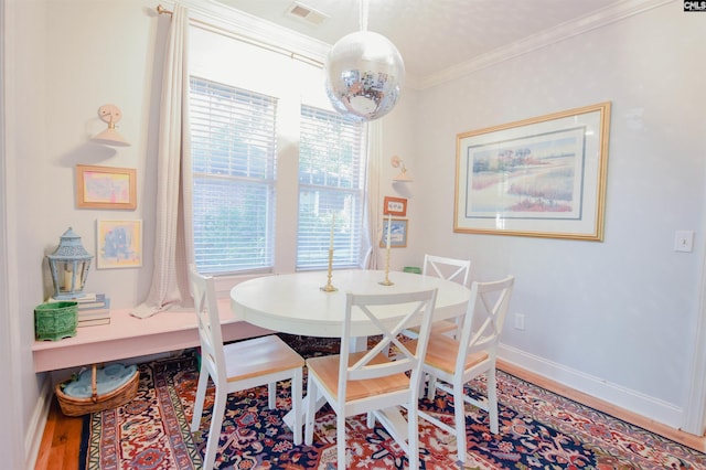 dining space with crown molding, wood finished floors, and baseboards