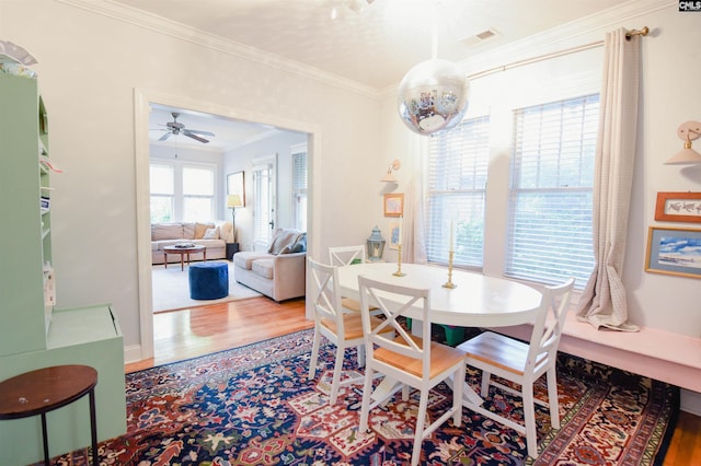 dining space featuring wood finished floors, ornamental molding, and ceiling fan
