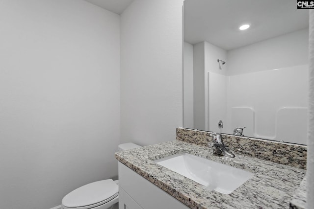 full bath featuring toilet, vanity, a shower, and baseboards